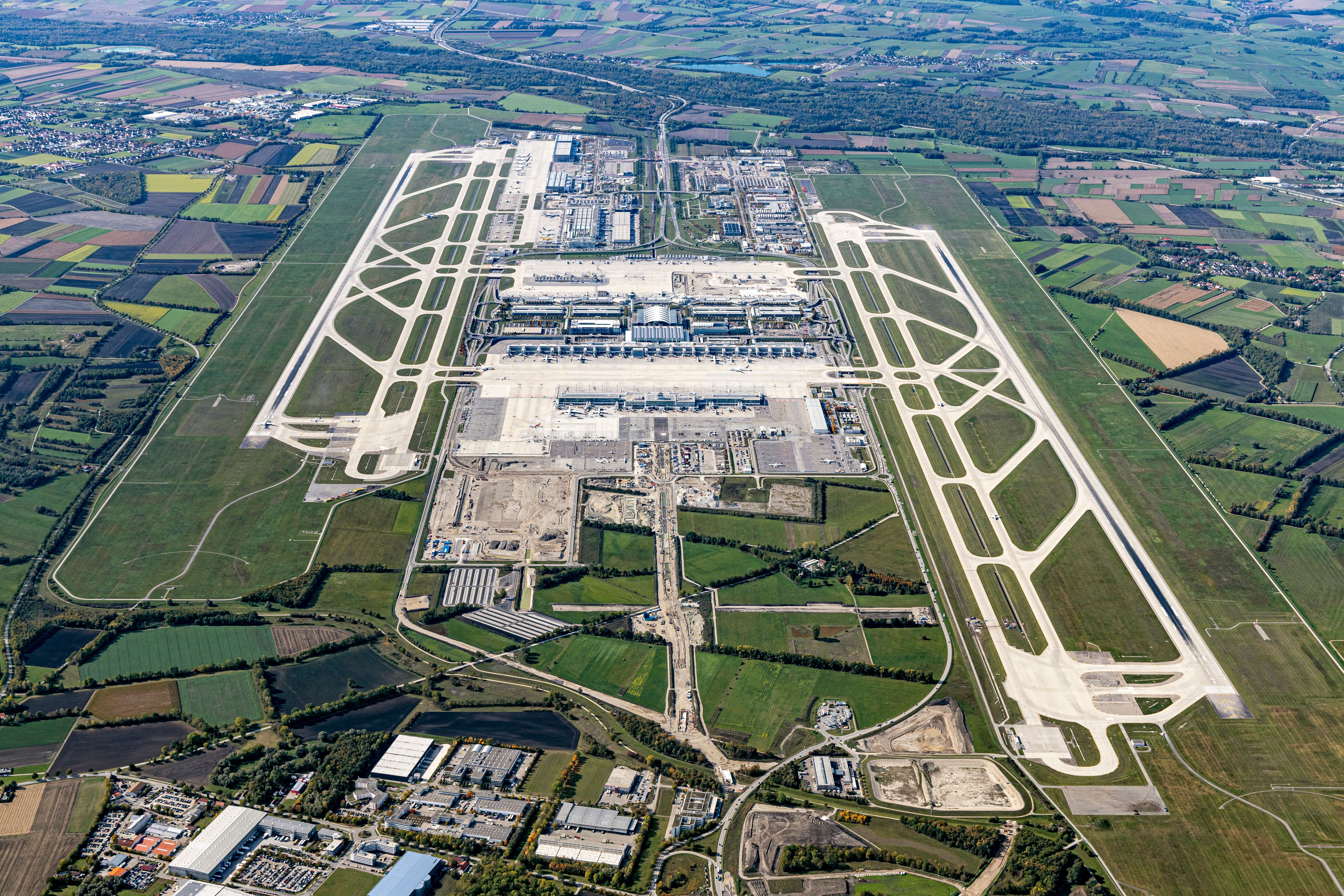 Aerial view of Munich Airport amidst a patchwork of fields and infrastructure.