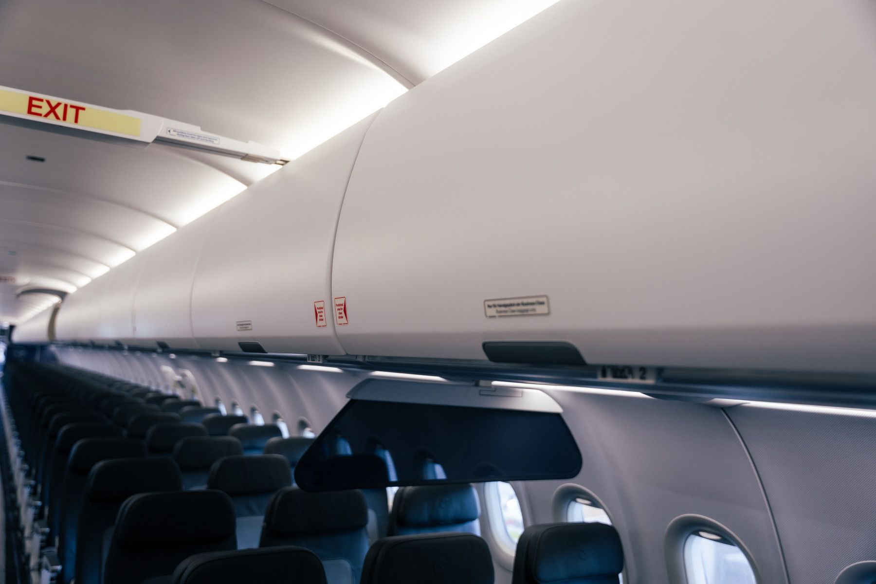 Empty airplane cabin showing overhead bins and seats, highlighting restricted storage space under new airline fare policies.