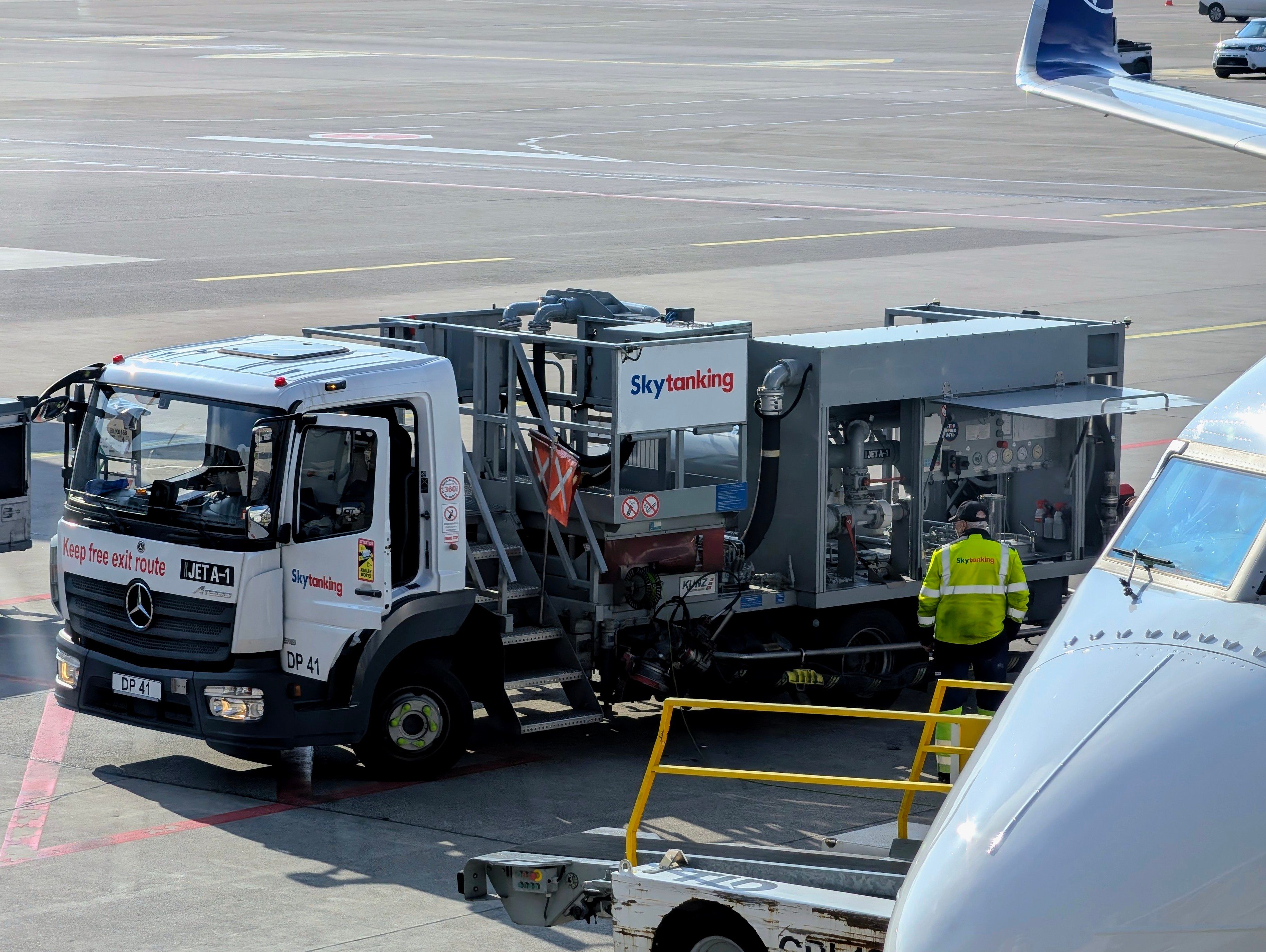 A Skytanking truck refuels a Lufthansa airplane on the tarmac at an airport.