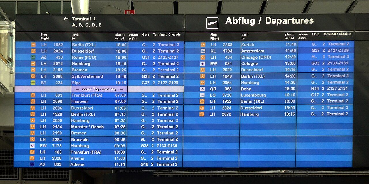 Flughafen-Abflugtafel mit Lufthansa-Flügen zu verschiedenen Städten. Fokus auf Destinationen, Flugnummern und Zeiten.