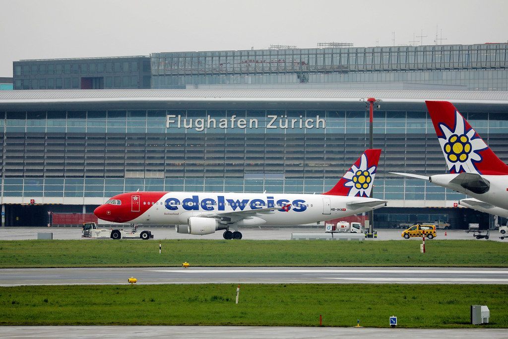 Edelweiss Air plane at Zurich Airport with airport building in the background.
