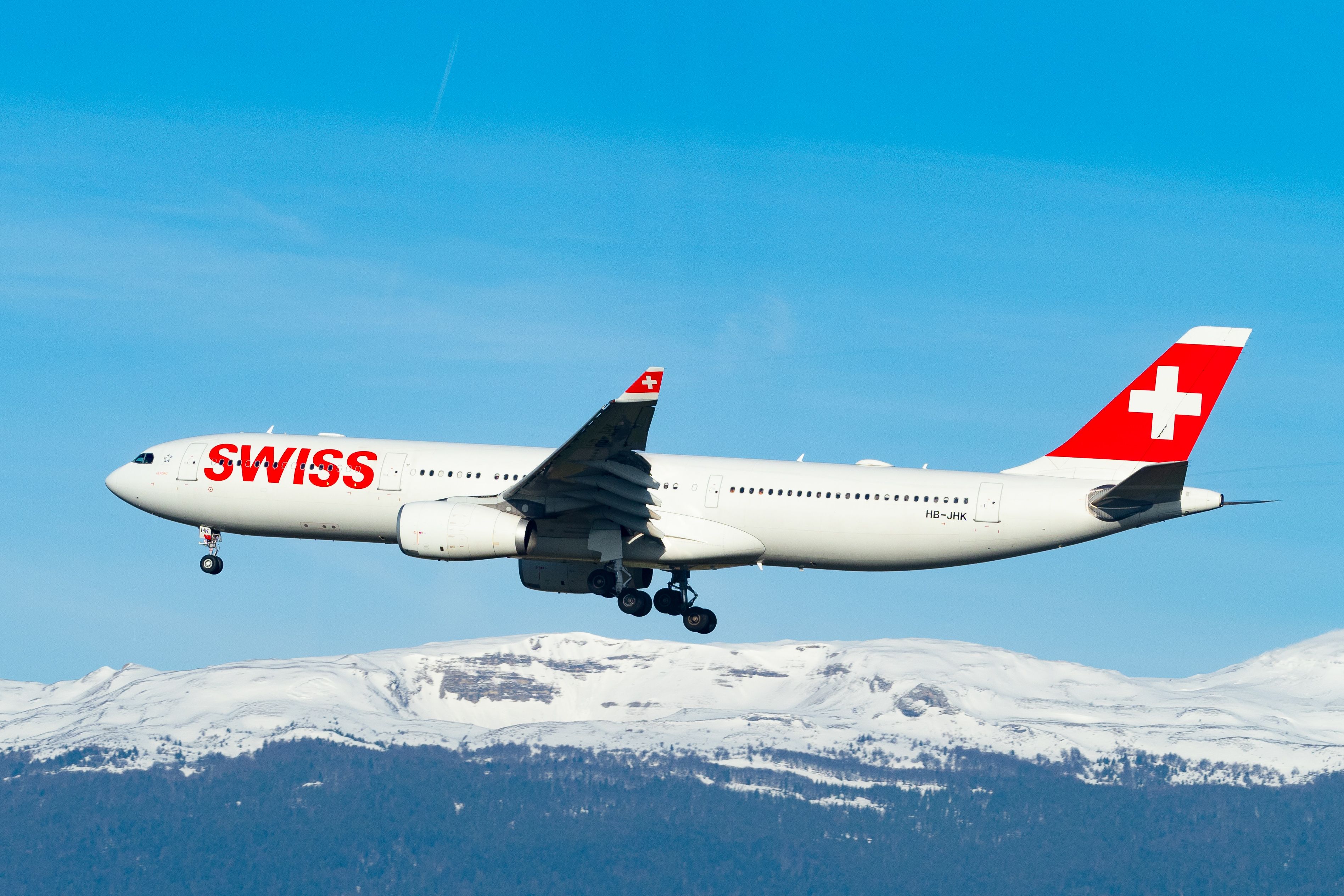 Ein Airbus A330-300 der SWISS (HB-JHK) im Sinkflug über schneebedeckte Berge im Jahr 2019 mit ausgefahrenem Fahrwerk.