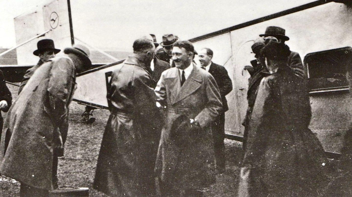 Adolf Hitler shaking hands in front of a Lufthansa plane.