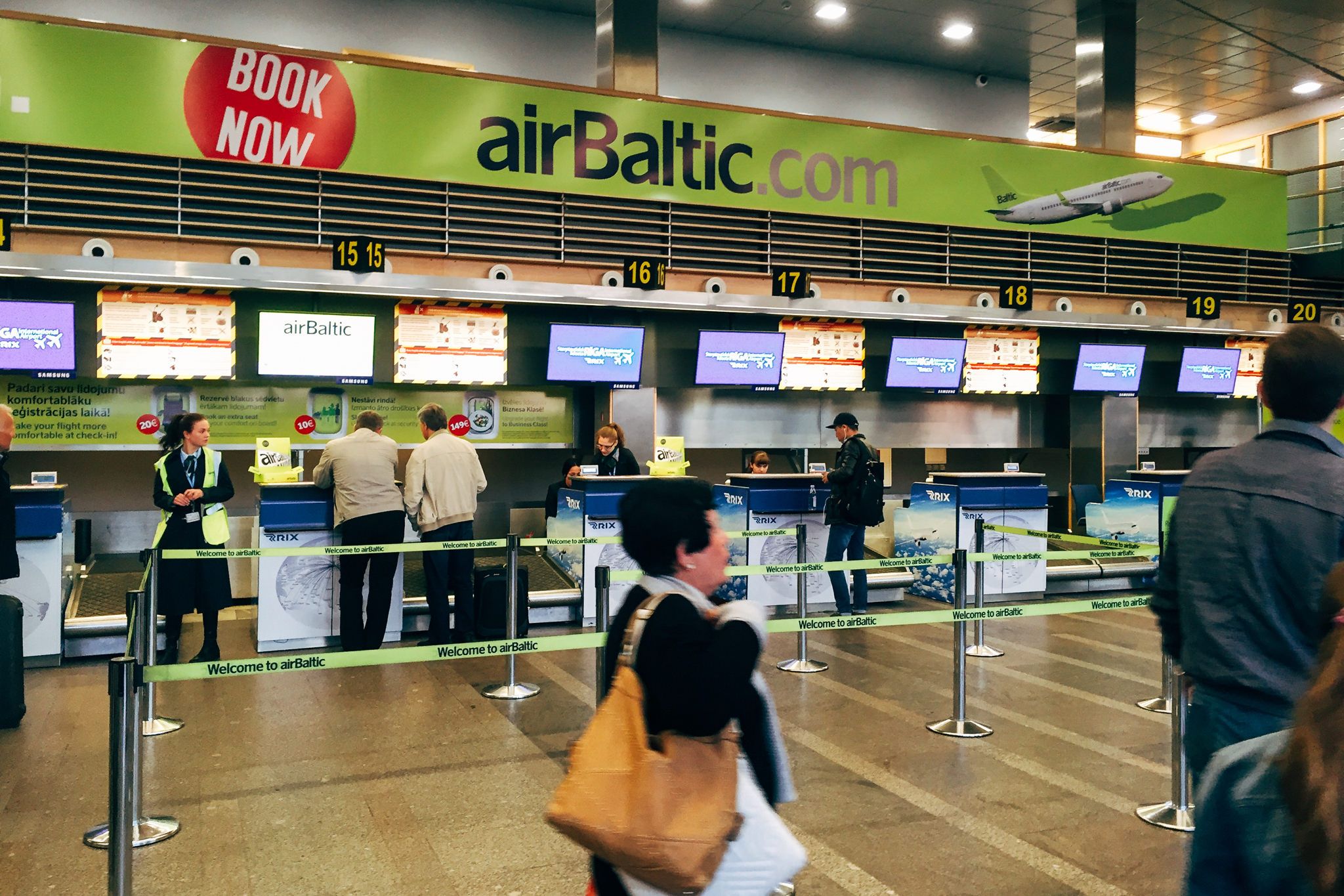airBaltic Check-in-Schalter am Flughafen Riga mit Passagieren und Personal.