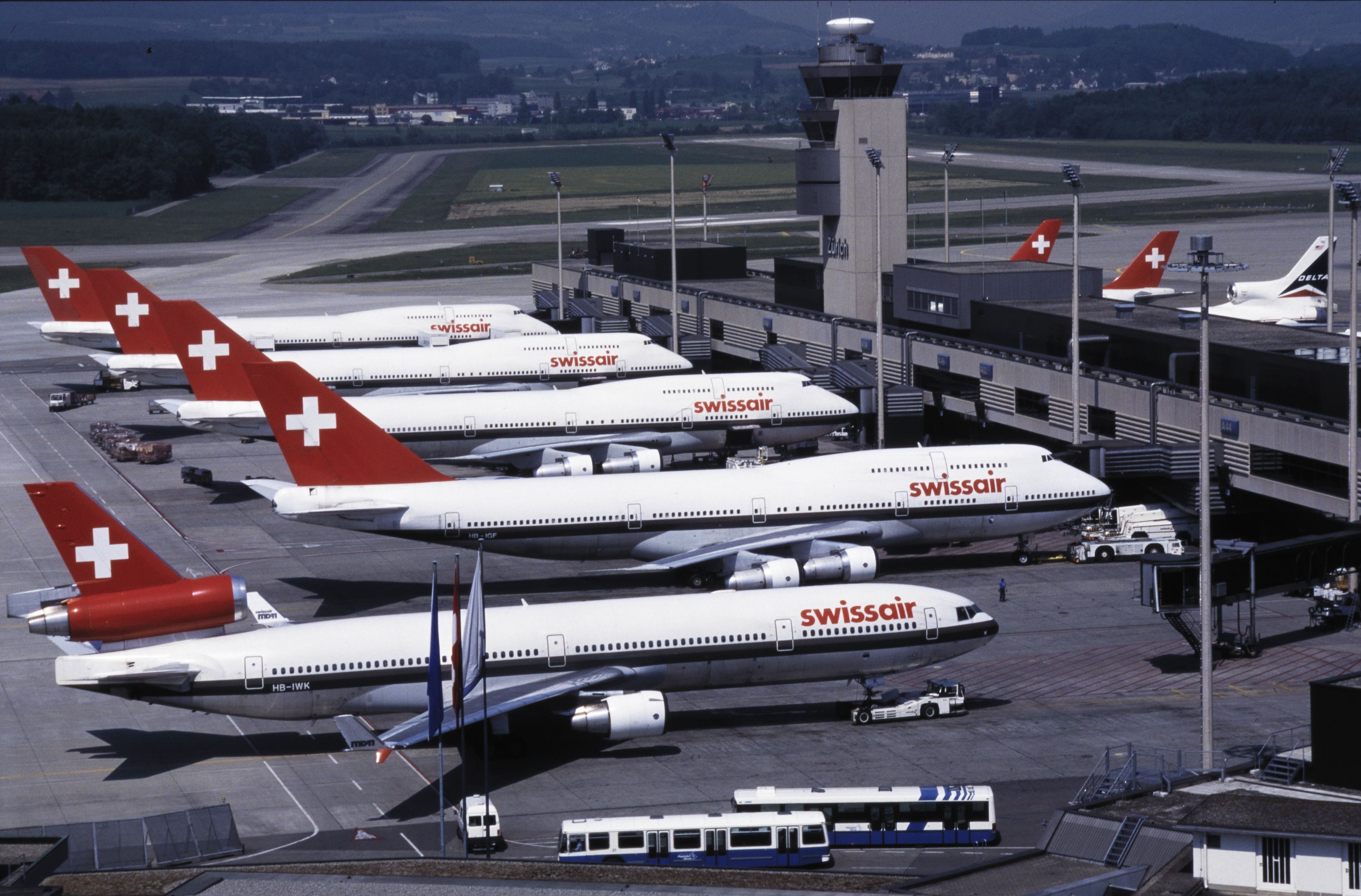 Swissair Boeing 747 und MD-11 am Flughafen Zürich mit Kontrollturm; ein Delta-Flugzeug ist auch sichtbar.
